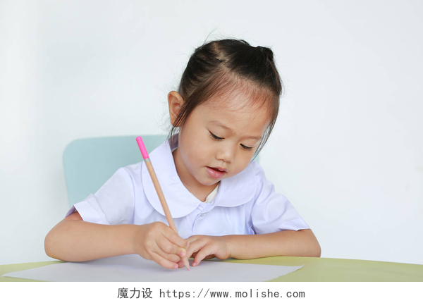 黑色背景墙前写东西的女孩穿着校服的亚洲儿童在白色背景下的桌子上写字.